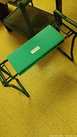 Green garden kneeling and sitting bench showing full padded surface and metal frame.