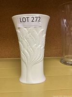 Front angle view of white porcelain vase with embossed leaf design and flared rim, showing texture and shape.