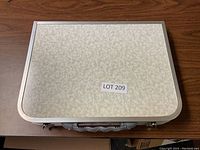 Portable folding picnic table folded into briefcase style showing beige marbled surface and carrying handle.