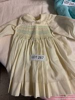 Front view of infant smocked dress in light yellow with long sleeves and Peter Pan collar.