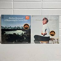 Front covers of two Barbra Streisand vinyl records in the lot: "A Happening In Central Park" and "Simply Streisand", both sealed with price and promotional stickers.