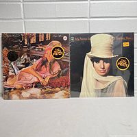 Two vinyl album covers displayed side by side featuring Barbra Streisand. Left cover shows 'Lazy Afternoon' with barbra in a pink dress lounging on a couch. Right cover shows 'My Name Is Barbra, Two...' with barbra in white hat and white clothing portrait.