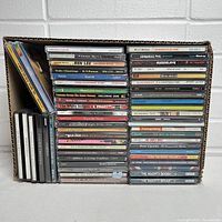 Photo showing the full box lot of 50 compact discs in jewel cases tightly packed in a cardboard box with titles visible
