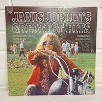 Front cover of Janis Joplin's Greatest Hits album featuring Janis on a motorcycle outdoors.