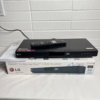 Black LG BD660C Blu-ray/DVD player unit with remote on top, set on original box. Box displays LG branding, Blu-ray Disc and DVD player designation, and 3D compatibility.