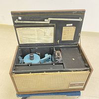 Front view of the Vintage Seeburg Encore Background Music System with the lid open, showing the internal turntable and mechanical components for background music playback. Labels and instructions are visible inside the lid.