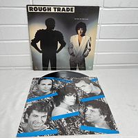 Photo showing the vinyl record partially outside the inner sleeve, and the inner sleeve featuring black-and-white portraits of band members with blue accents.