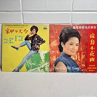 Two vintage Chinese vinyl record albums upright showing front covers. Yellow cover with dancing woman and red cover with woman in blue qipao.