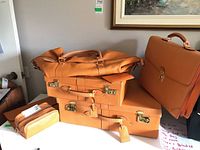 Five-piece arrangement: two suitcases stacked with duffle bag on top, briefcase at side, toiletry pouch in front