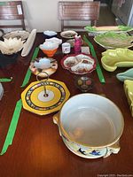 View of assorted china items including serving dishes, miniature vases, an ashtray, on a dining table
