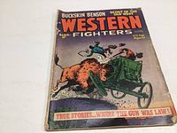 Front cover of Western Fighters comic book showing action scene with cowboy shooting from a buggy at bison.