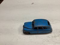 Front and side view of the blue die-cast Vanguard toy car showing play wear and scratches