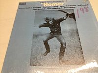 Front cover of Homer soundtrack record with light blue background and black and white photo of man jumping, listing featured artists.