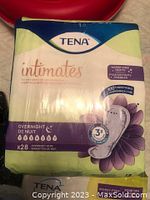 Photo of unopened package of Tena Intimates overnight absorbent pads with 28 pads inside, in cream, blue, and purple packaging.