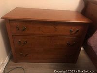 Front view of antique solid wood dresser showing three drawers with metal hardware.