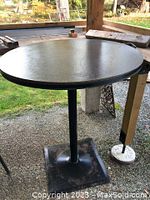 Photo of round metal bistro table with square base showing surface and support structure
