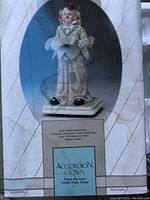 Front view of the accordion clown figurine music box inside a plastic dome showing details of clown's face, outfit, and accordion.
