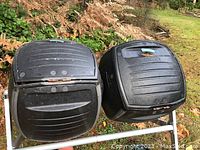 Photo of black dual rotating composter barrels on metal frame outdoors