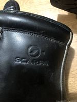 Close-up of the outer side of a black Scarpa boot showing the embossed Scarpa logo