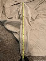 Full length measurement of the beige outdoor cover showing approximately 68 inches in length.