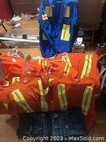 Lot contents showing 3 orange safety T-shirts without pockets with reflective stripes, 3 blue denim work jeans, and 1 blue safety jacket with reflective stripes.