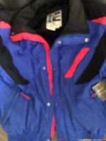 Front view of vintage Helly Hansen ski coat showing blue, black, and red color scheme and front zipper with snap buttons.