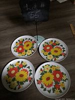 Four vintage Melmac dinner plates arranged face up showing floral pattern