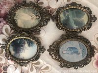 Four oval metal frames with vintage styled pictures inside, showing decorative metal filigree around edges.