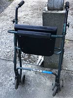Photo of the walker back and rear wheels showing folded padded armrests and seat.