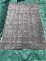 Gray weighted blanket laid out on green tarp showing full size and quilted squares.