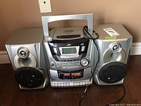 Front view of JVC boom box with CD player, cassette deck, and speakers connected.