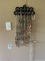 Necklaces hanging on black plastic organizer with a variety of styles and beads