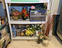Shelves holding various faux floral arrangements, stoneware, ceramic containers, and tote