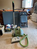 Full view of Shark cordless sweeper and Bissell Little Green Machine carpet cleaner with accessories and floor background.