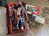 Photo of orange plastic toolbox section with hand tools like hammer, pliers, tape measure, screwdrivers, along with Jobmate rotary tool accessory kit box and safety glasses in carrying case.