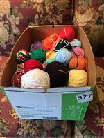 Box with assorted yarn balls of different colors and types.