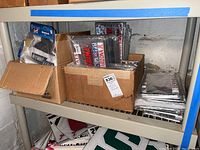 Boxes on shelf containing unopened NCAA license plate frames and flags/windsocks.