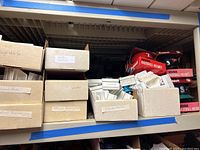 Shelves with labeled boxes containing mini helmets and car flags for multiple MLB teams, including White Sox and Reds