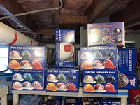 Photo showing eight boxes of hard hats on a shelf with various NCAA logos visible on the helmets inside the boxes