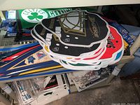 Stack of NHL goalie mask shaped and traditional team pennants including Boston Bruins and Chicago Blackhawks visible, laid on table