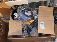 Box containing multiple plastic-wrapped NFL ball caps in various team colors.