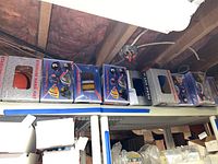 Photo showing 10 NFL hard hats in unopened original boxes lined up on a shelf in a basement setting.