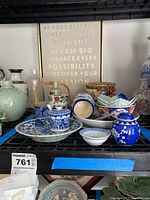 Front view of assorted Asian plates, candy dishes, blue and white porcelain items, spoons, condiment container, and Tiffany & Co. bowl.