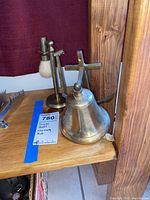 Photo shows the brass bell and brass shaving kit stand with brush and razor on a wood surface.