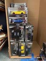 Stack of boxed die-cast cars showing silver sports car, yellow Mustang and blue pickup
