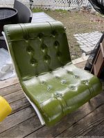 Front angled view of the green vinyl scoop chair showing button tufting and vinyl texture.