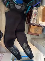 Photo showing black full wetsuit laid out, with knee pads visible on knees.