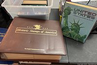 Brown leather-bound Historic Stamps of America album with embossed gold text and eagle emblem on cover.