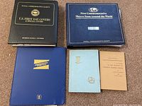 Photo of the five binders and books in lot including stamp collections and coin collecting books.