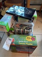 Photo of the stacked items including the tomato planter box, charger box, and other boxed items for identification and condition.
